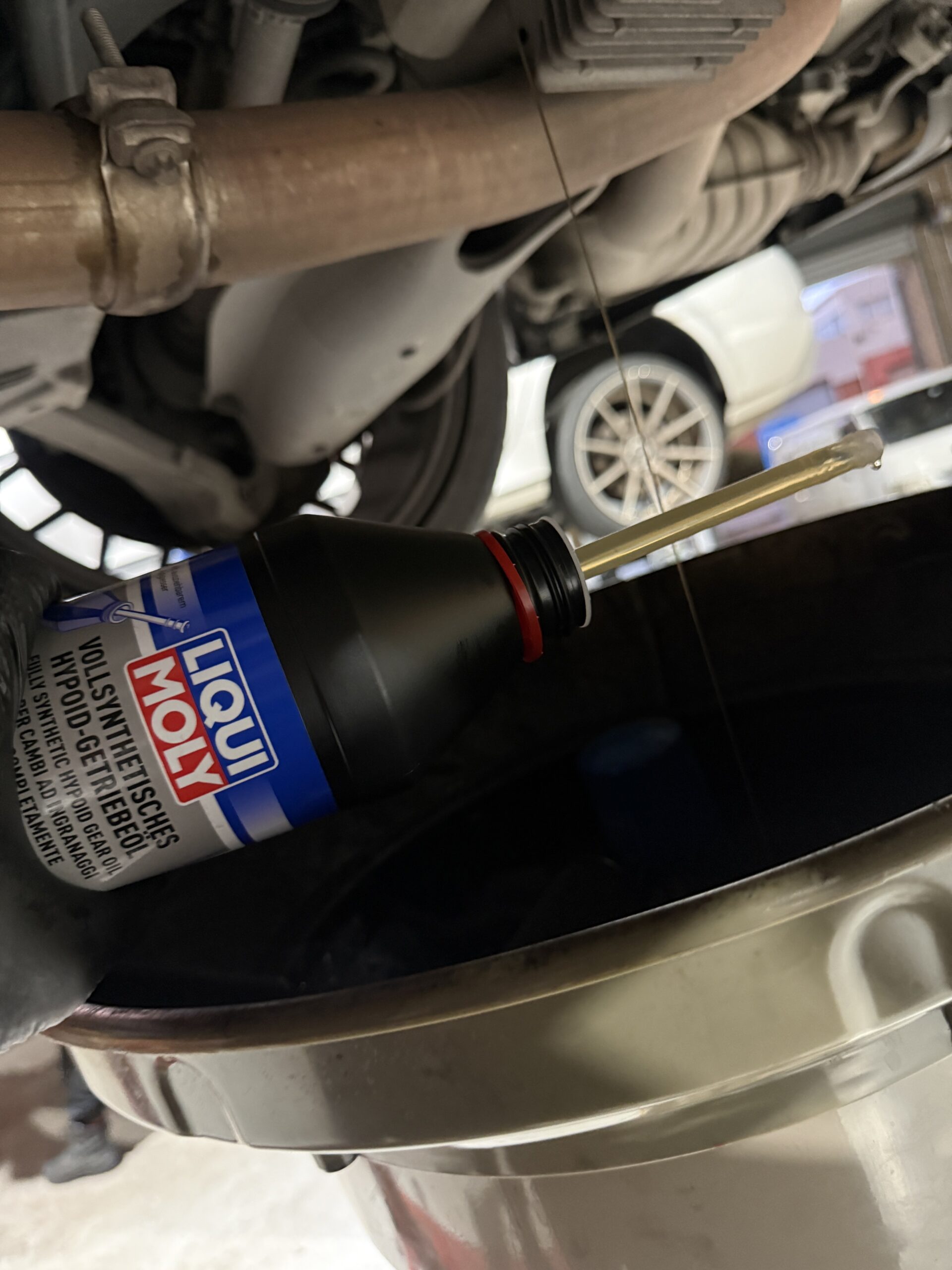 Liqui Moly gear oil container beside a vehicle during driveline fluid servicing.