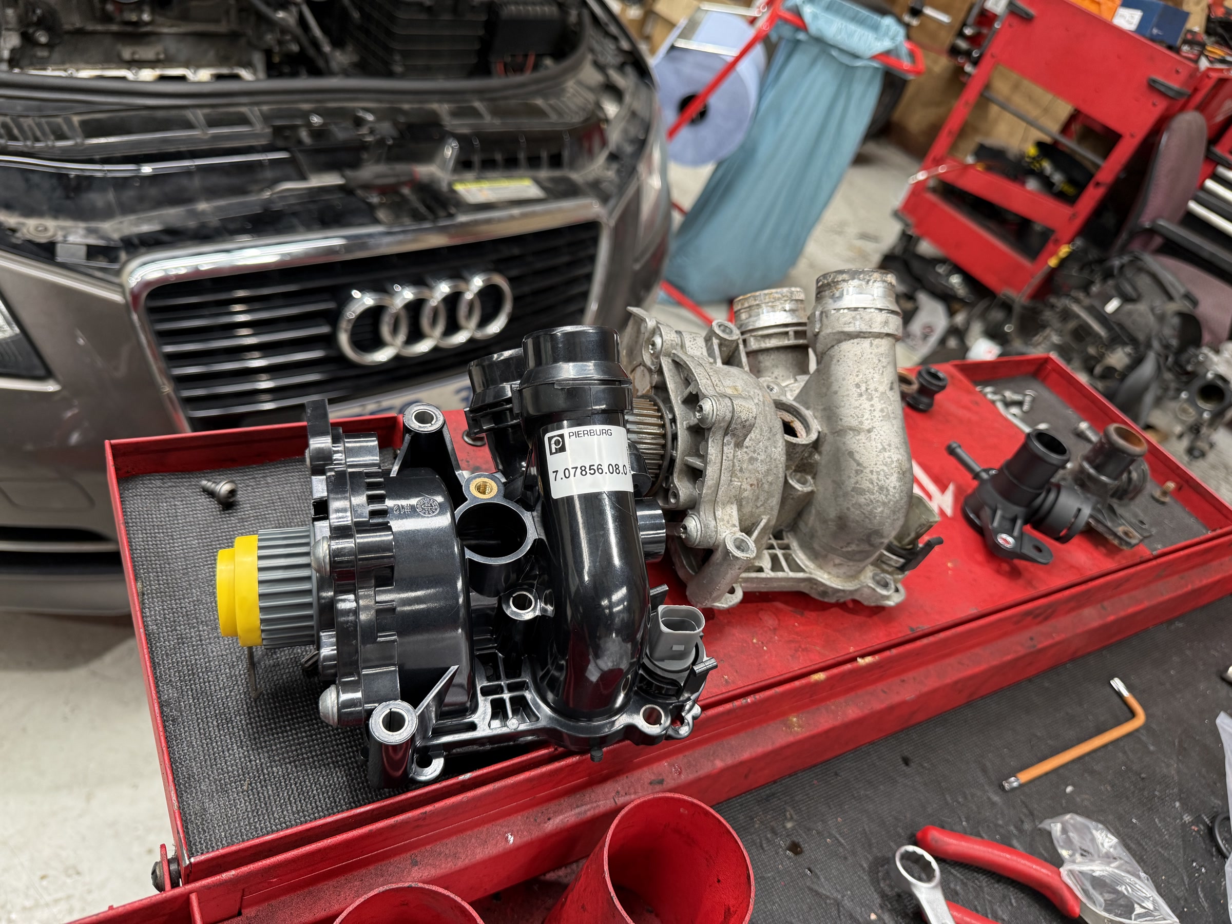 Workshop view of old and new cooling-system components for a 2012 Audi A3 convertible at Luca Motors.